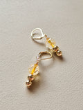 Gold and clear bead earrings on a light gray background