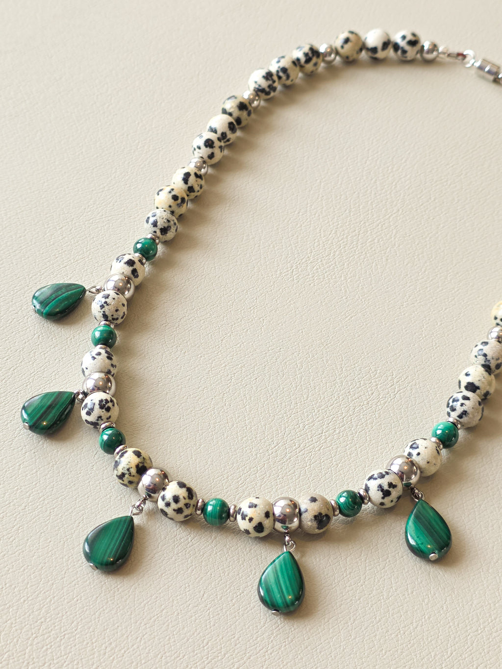 Wide view of dalmatian jasper stones and teardrop shaped malachite stones on necklace