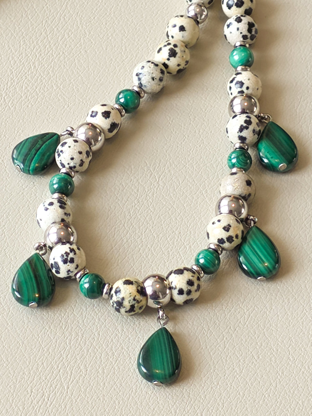 Close up view of malachite stones on a necklace, rich with green banding