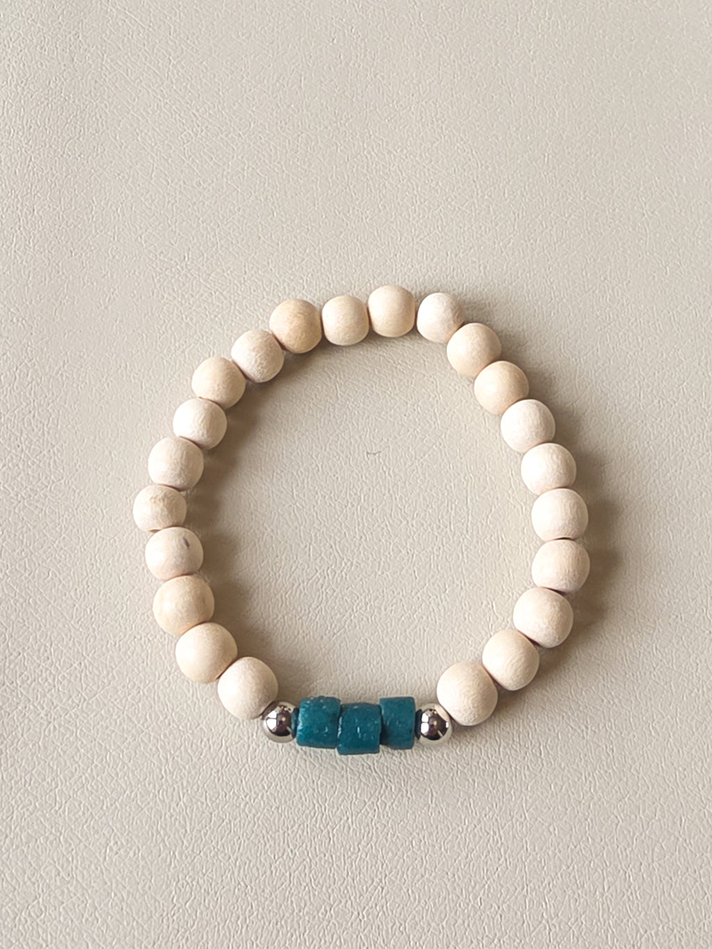 White beaded bracelet with blue and silver beads on a light gray background